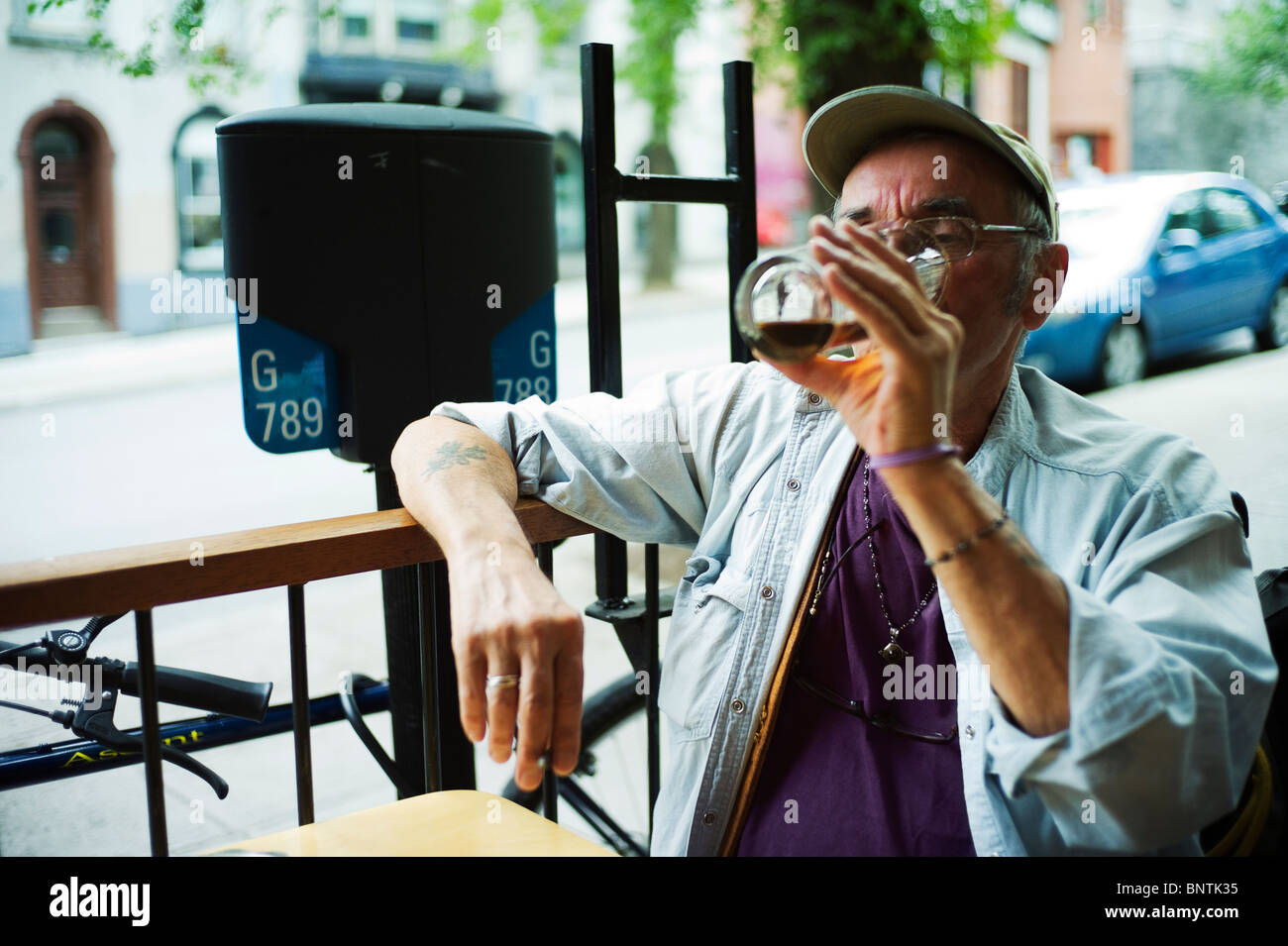 Old man finishes a pint of beer while sitting on bar terrace. Stock Photo
