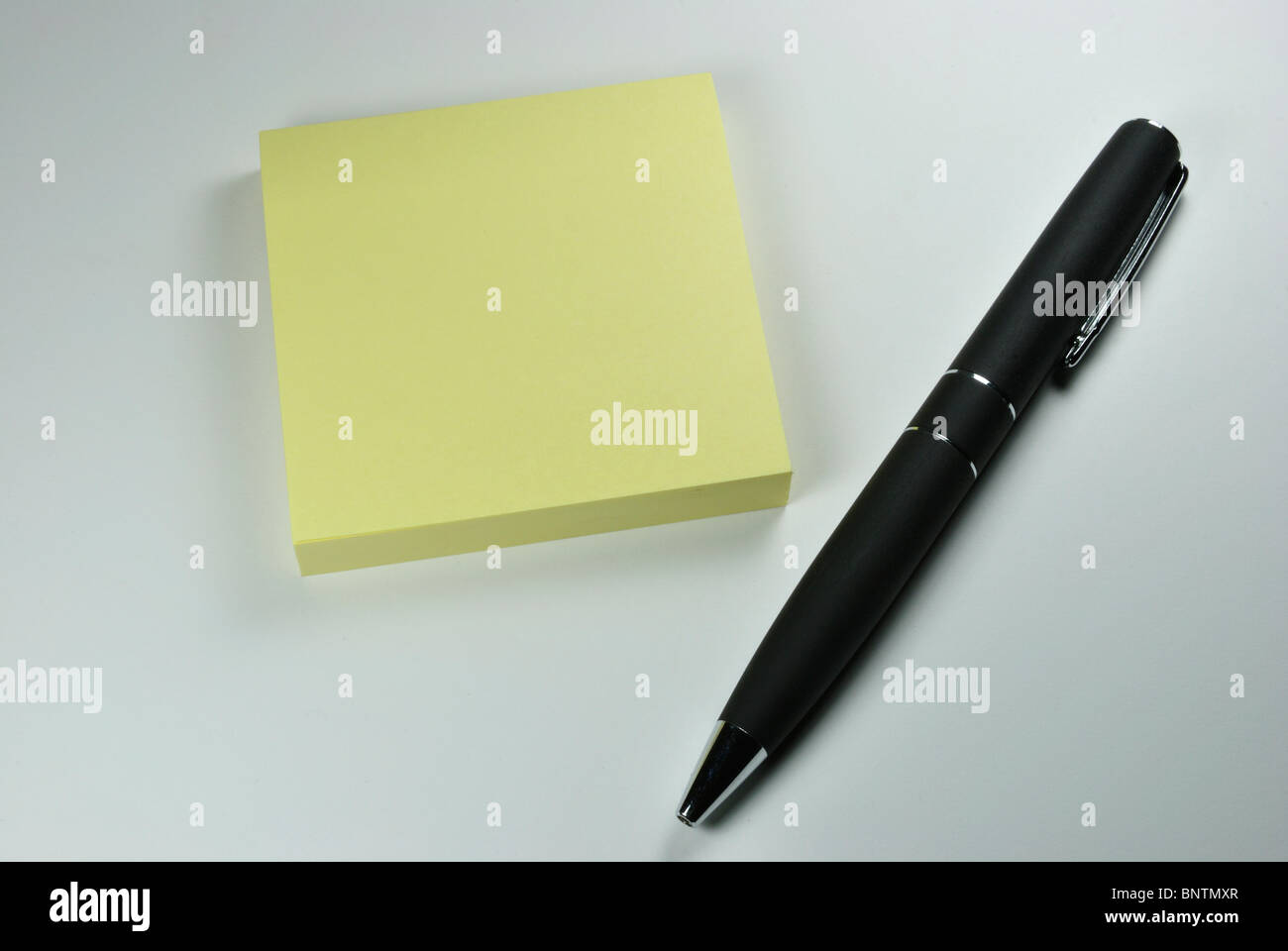 Black pen laying next to book of sticky notes Stock Photo