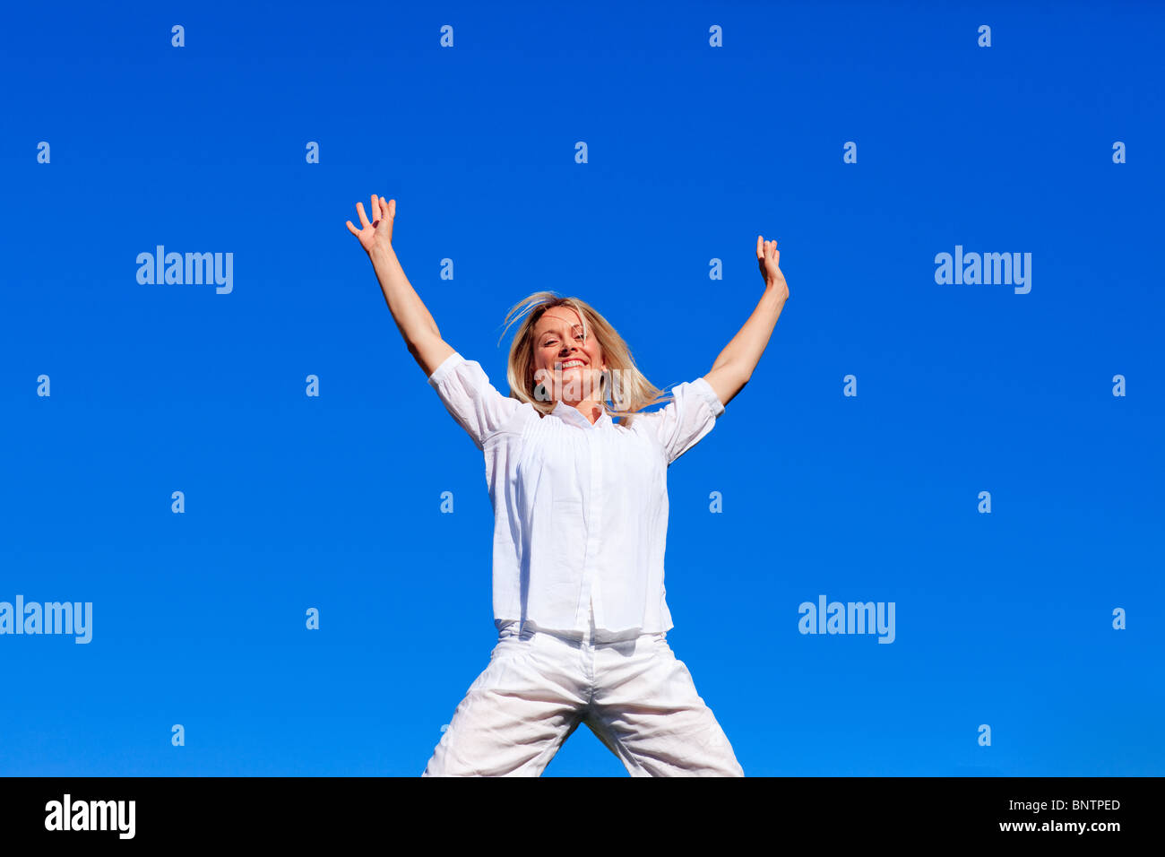 Happy girl jumping against blue sky Stock Photo - Alamy