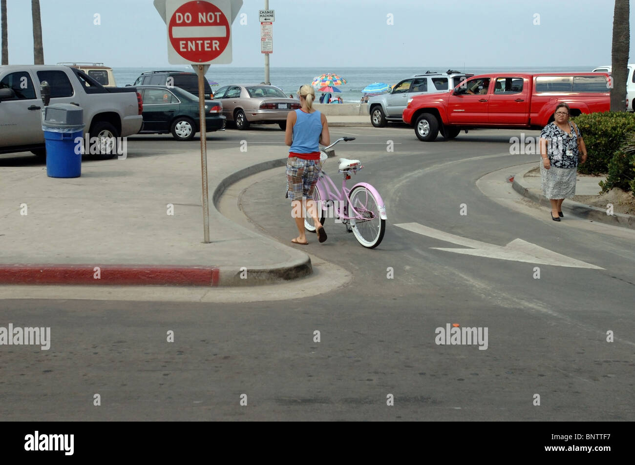 Woman walking with her pink beach cruiser bicycle in Newport Beach
