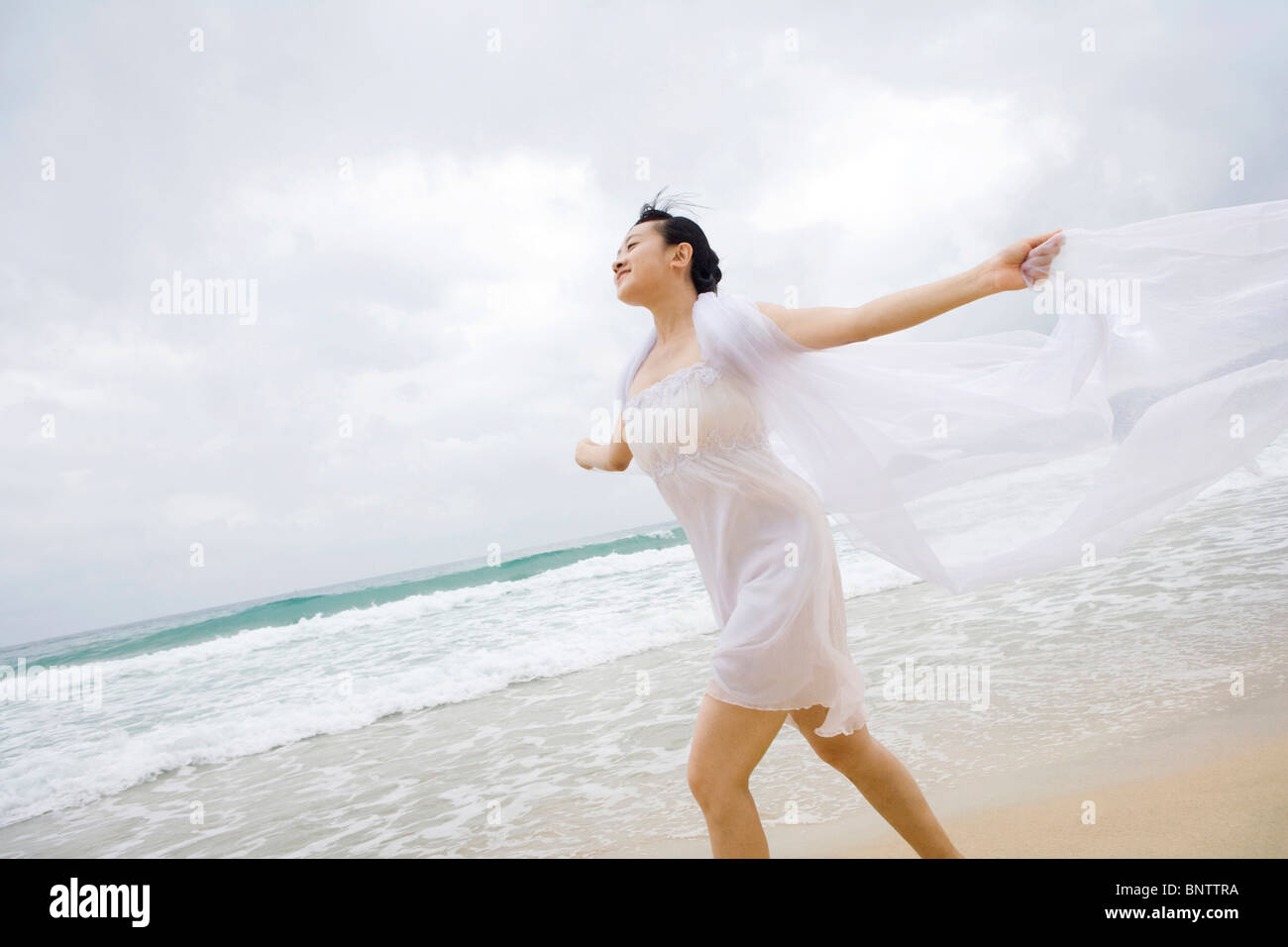 Portrait of a young woman running along the beach Stock Photo - Alamy