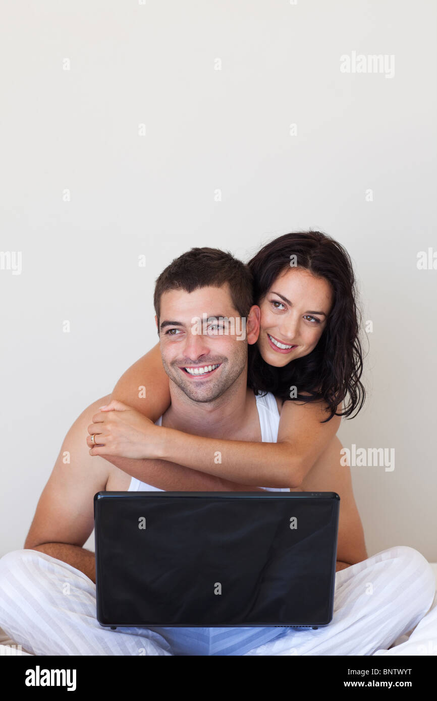 Lovely couple using a laptop on a bed Stock Photo - Alamy
