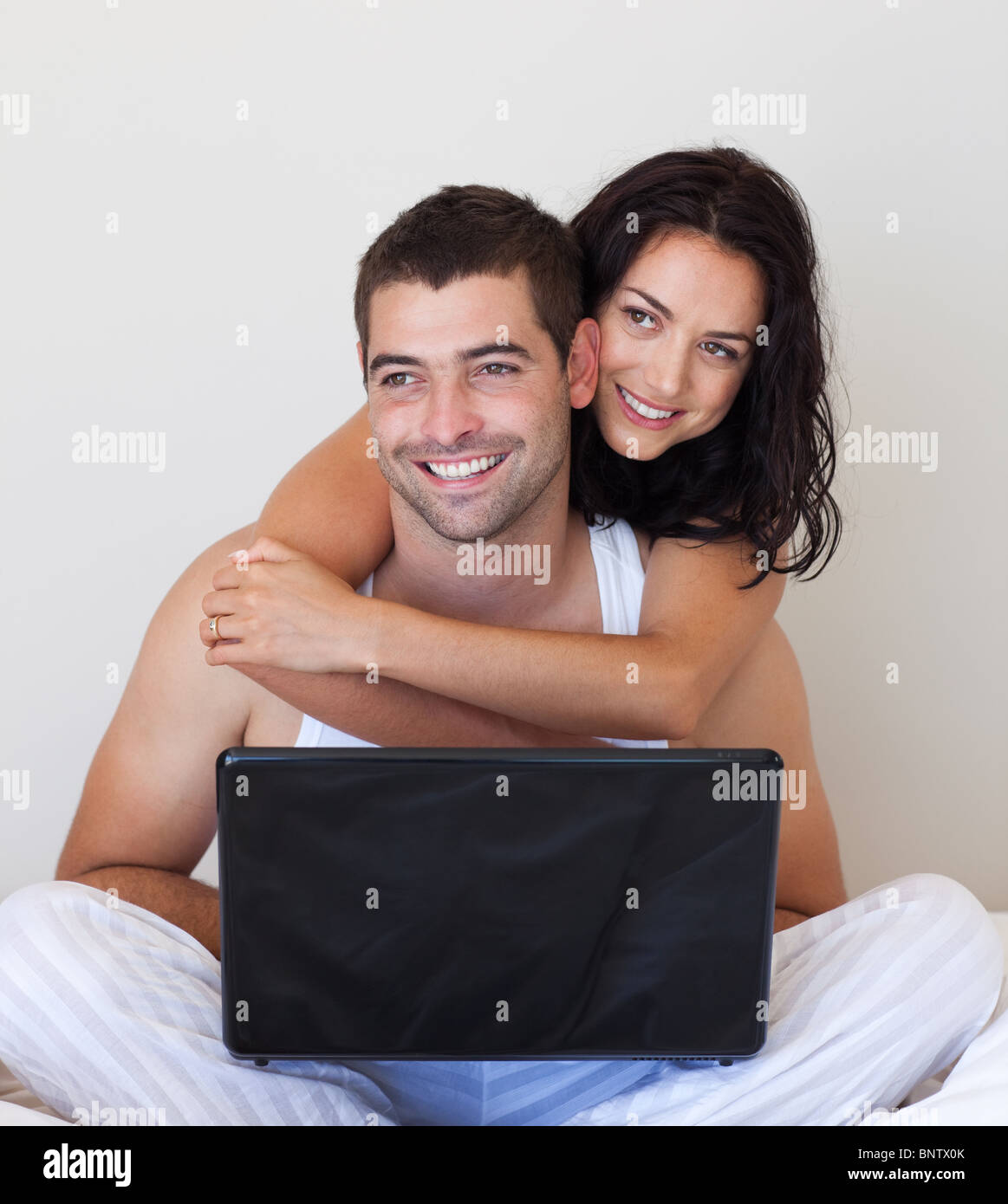 Smiling couple using a laptop on a bed Stock Photo Alamy