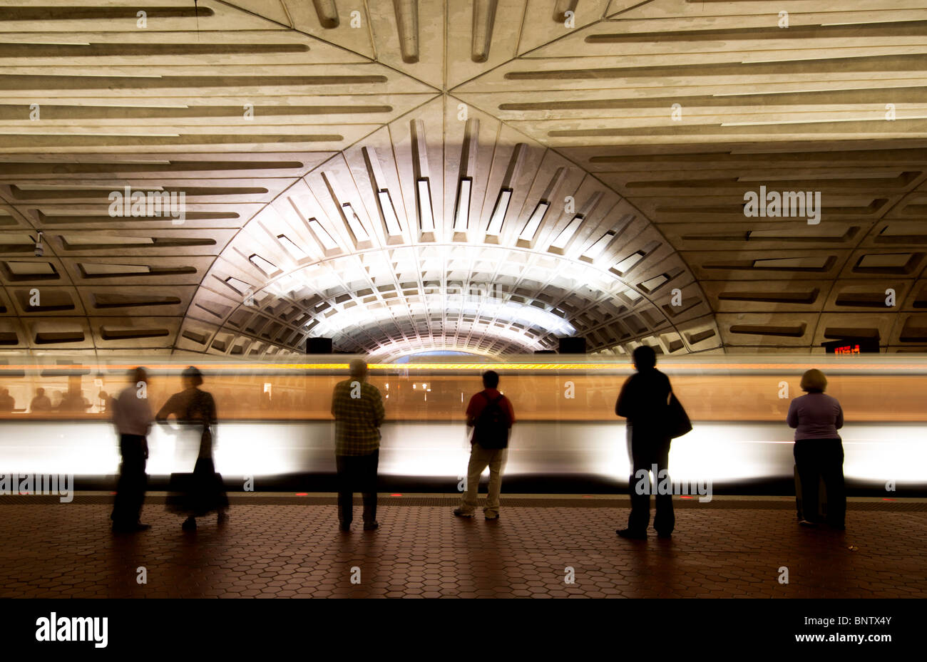 Commuters/passengers waiting for a train on a metro station platform as a train leaves the station in Washington DC USA Stock Photo