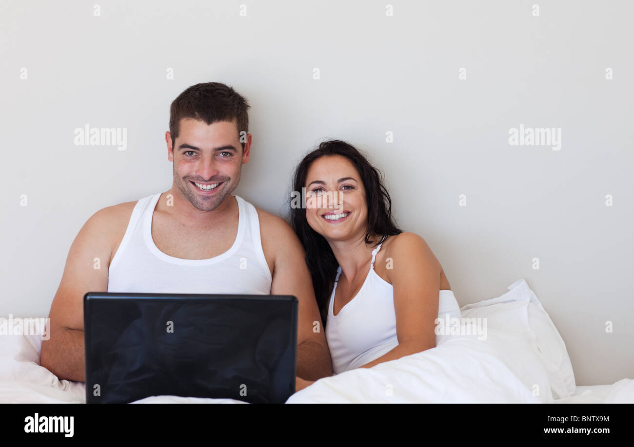 Жена связала мужа русское. Пара на кровати с ноутбуком. Счастливая пара сидит на кровати. Муж с женой в кровати Сток. Муж с женой сидят за компьютером.