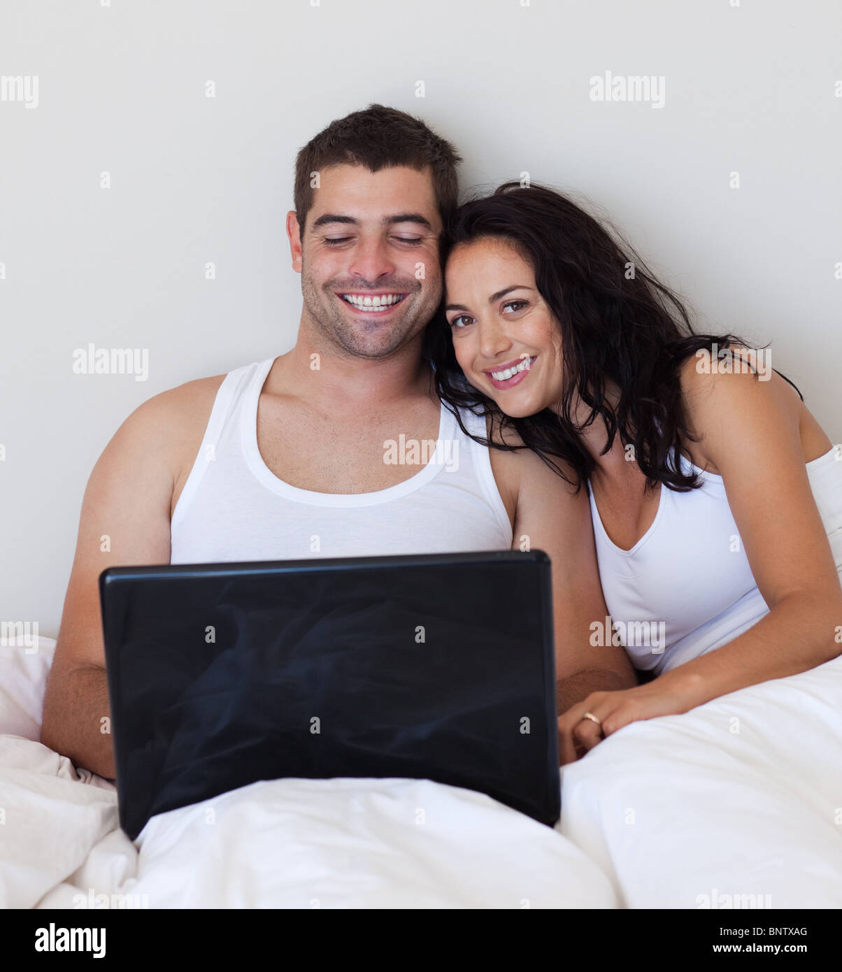 Attractive couple using a laptop on a bed Stock Photo Alamy