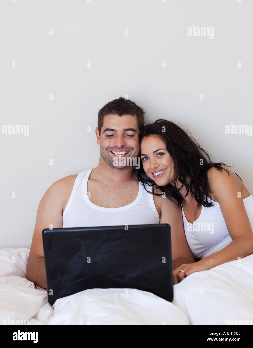 Delighted couple using a laptop on a bed Stock Photo - Alamy