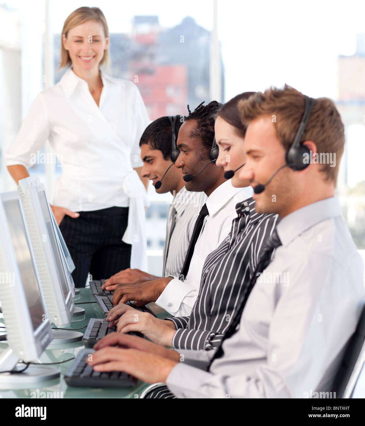 Happy female leader with a team on a call center Stock Photo