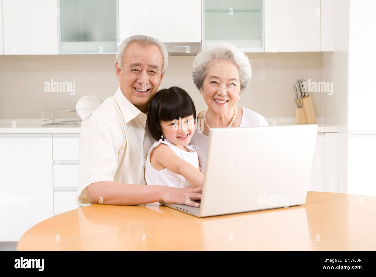 Little girl using a laptop with her grandparents Stock Photo - Alamy