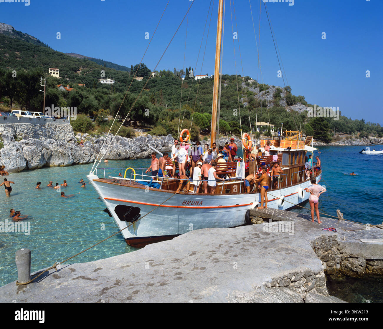 Excursion boat visiting the picturesque fishing village of Nissaki Stock Photo