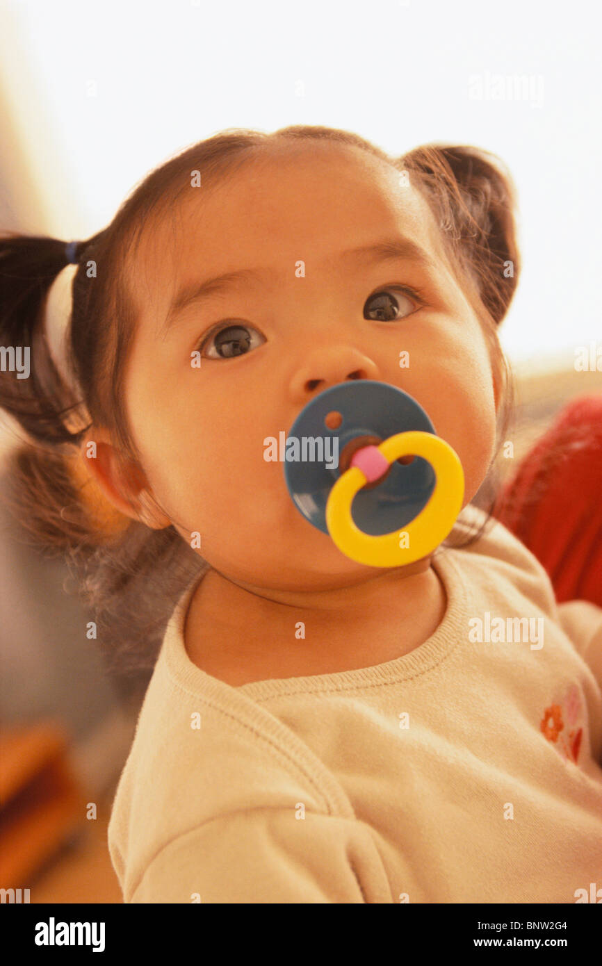 Infant with a pacifier in her mouth Stock Photo Alamy