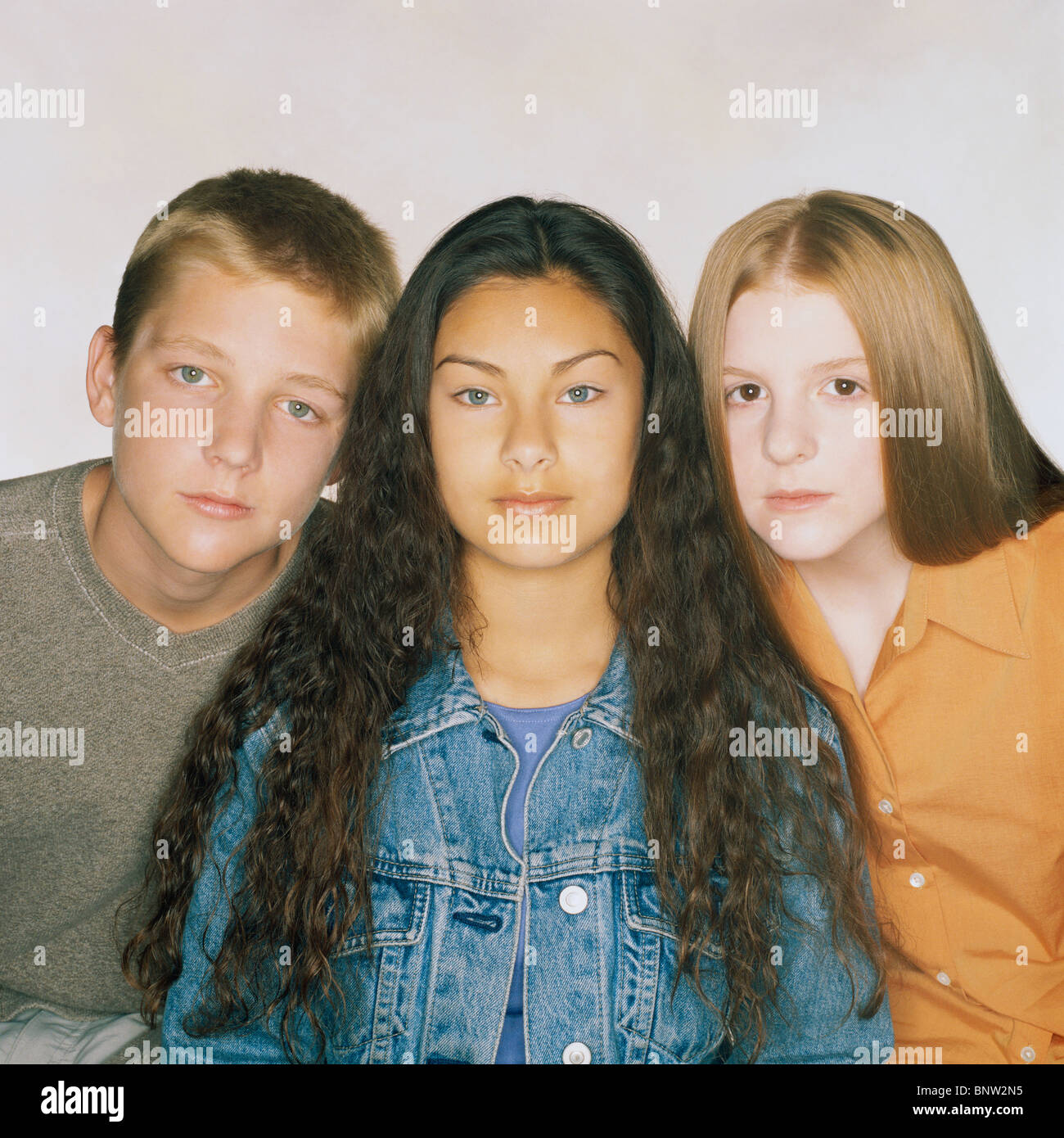 Three teenage friends sitting in a row Stock Photo