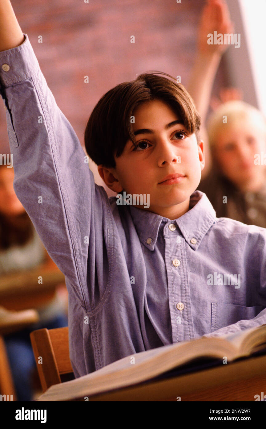 Elementary school student raising his hand in classroom Stock Photo - Alamy