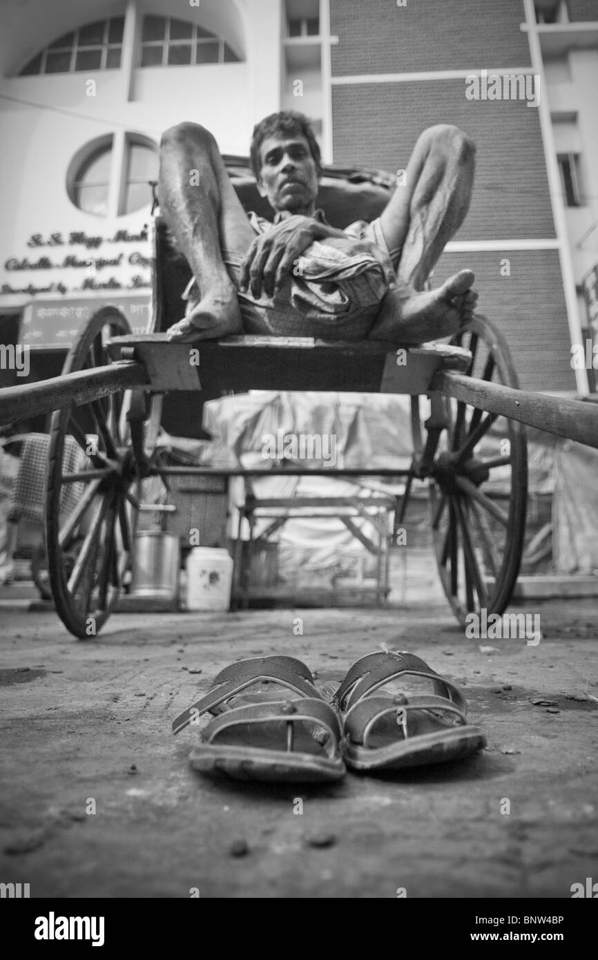 A rickshaw puller takes a well earned break on the streets of Kolkata (formally known as Calcutta) Stock Photo