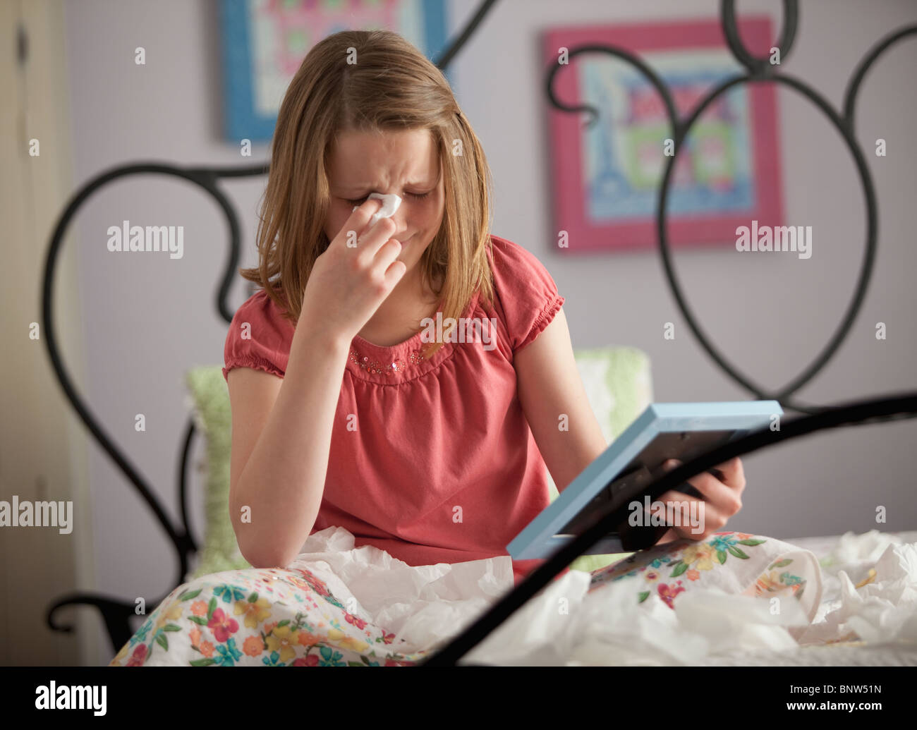 Young girl crying while looking at photograph Stock Photo
