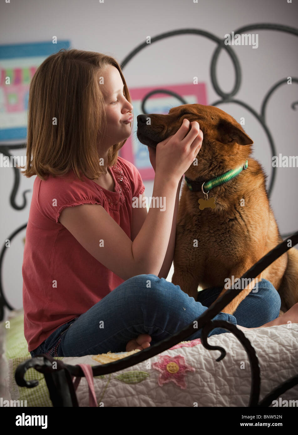 Young girl playing with dog on bed Stock Photo