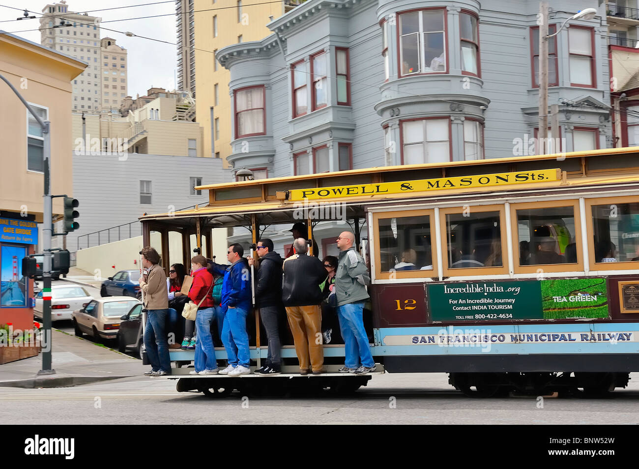 Tourists passengers riding classic cable car a/k/a trolley car or tram, San Francisco, California, USA Powell and Mason Street Line Stock Photo