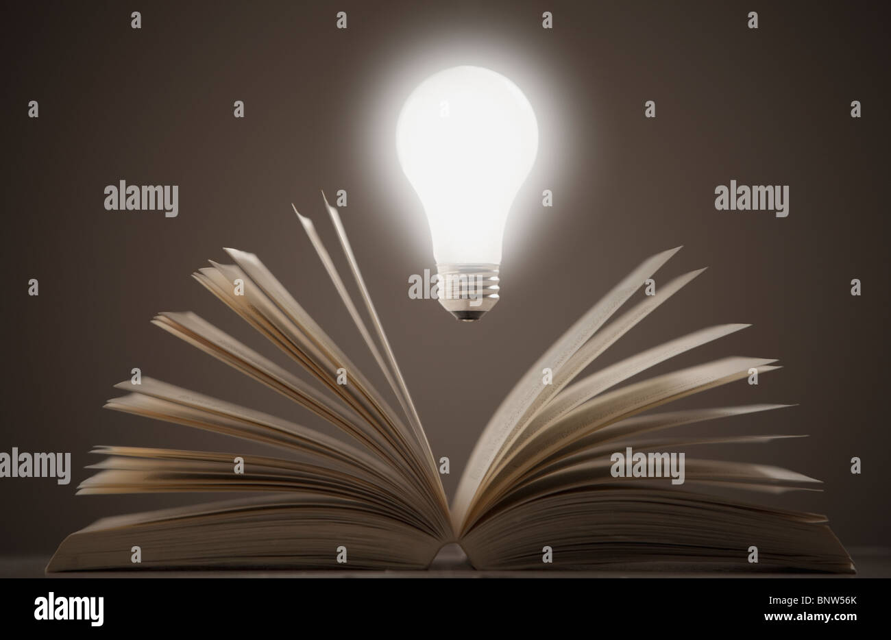 Light bulb floating above open book Stock Photo