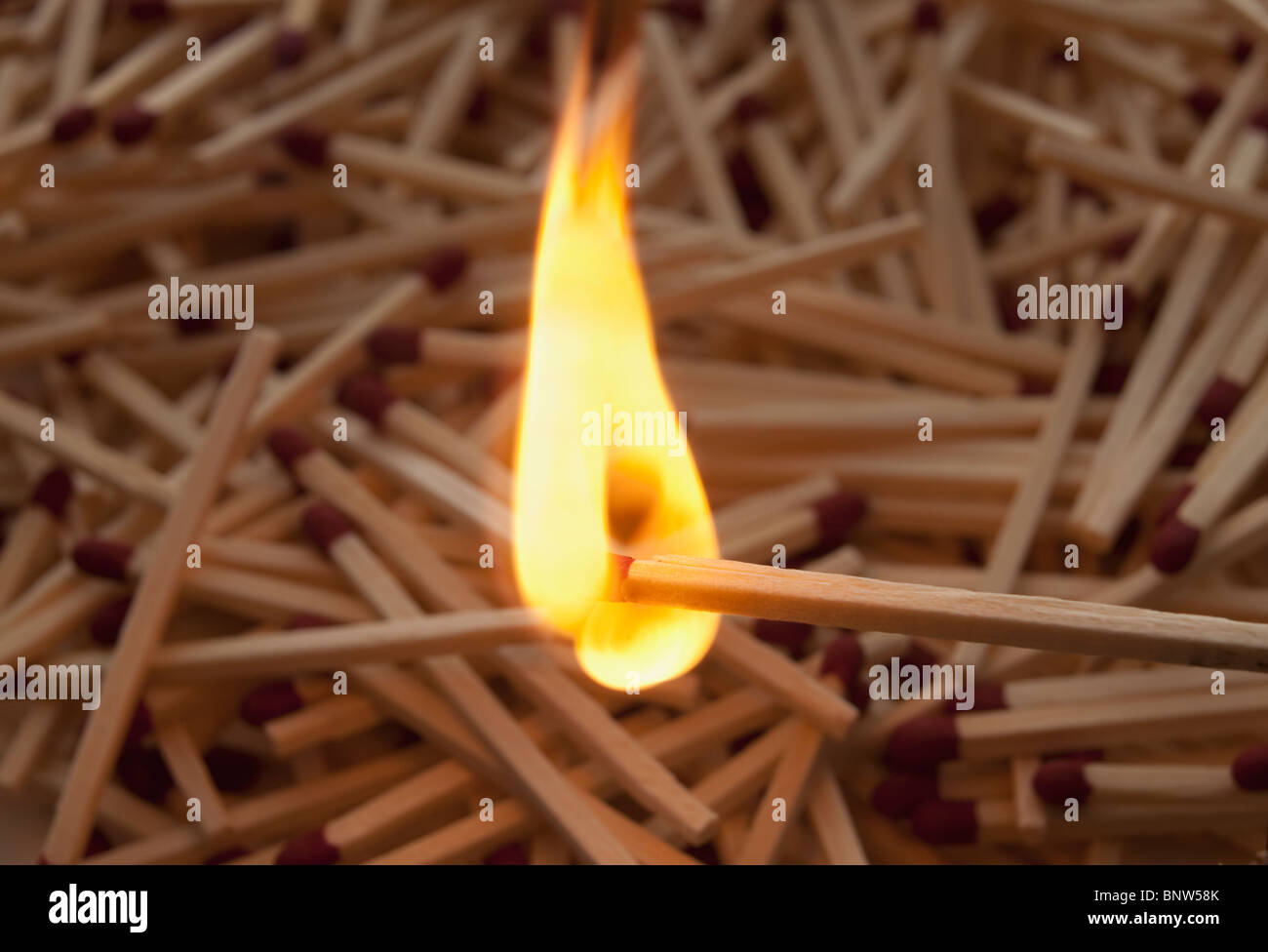 Lit match on top of a pile of wooden matches Stock Photo