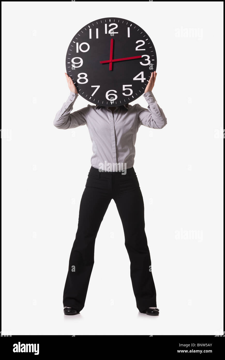 Businesswoman holding clock in front of her face Stock Photo