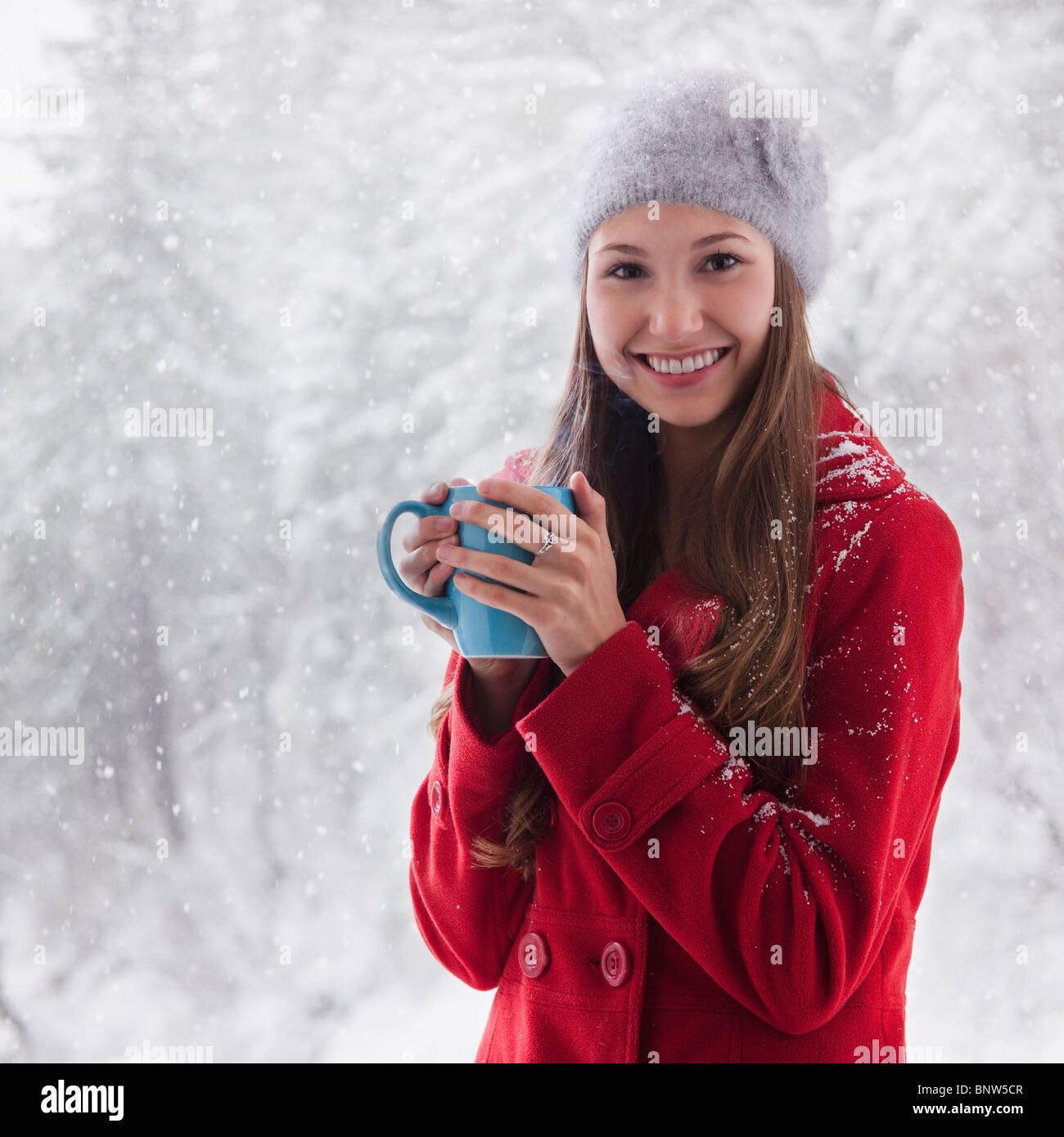 Woman in the snow holding a warm drink Stock Photo