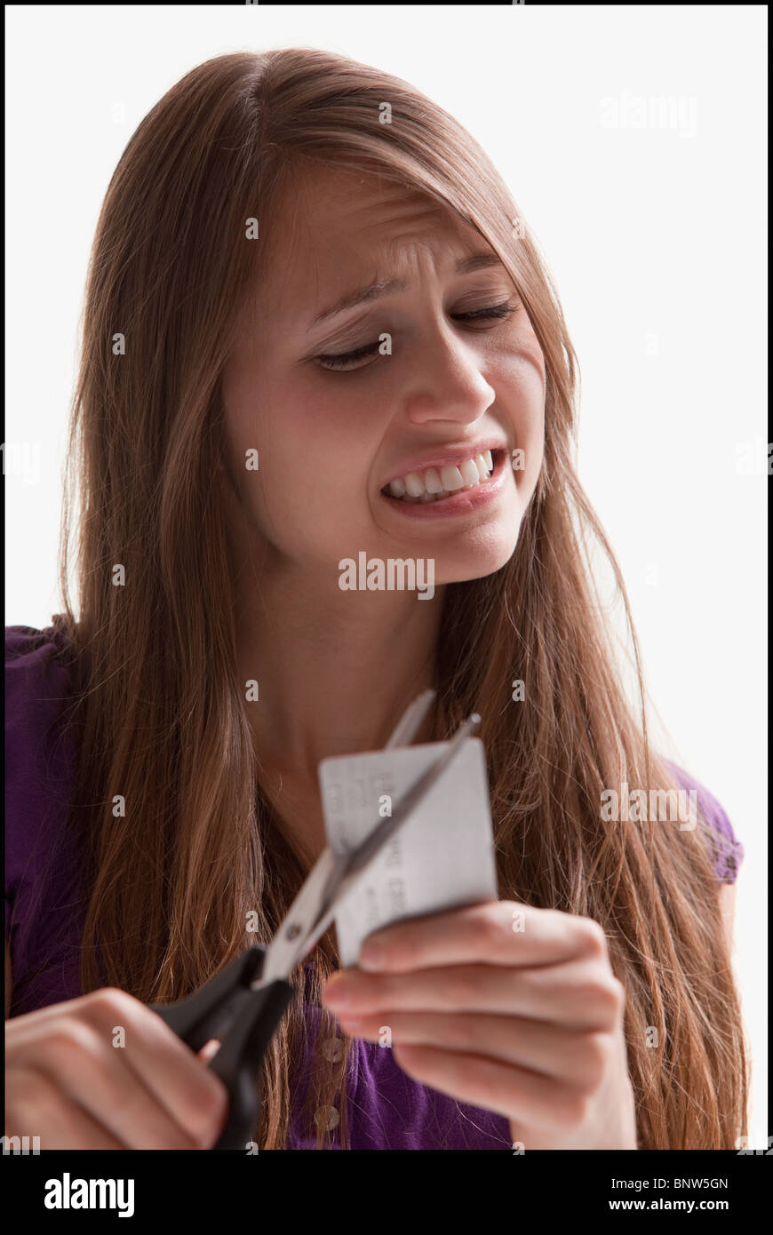 Woman reluctantly cutting her credit card Stock Photo