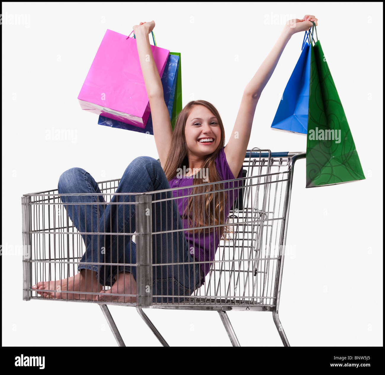 Excited woman sitting in a shopping cart with her purchases Stock Photo ...