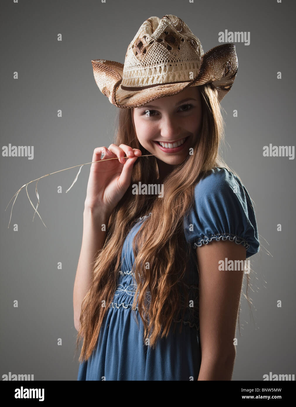 Beautiful long haired cowgirl chewing on grass Stock Photo