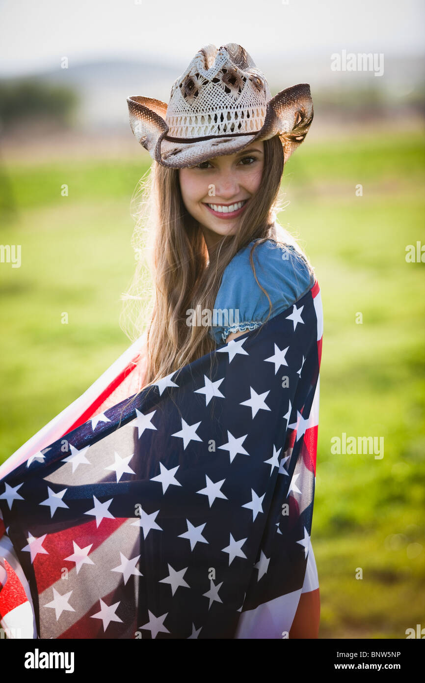 Beautiful cowgirl wrapped in American flag Stock Photo