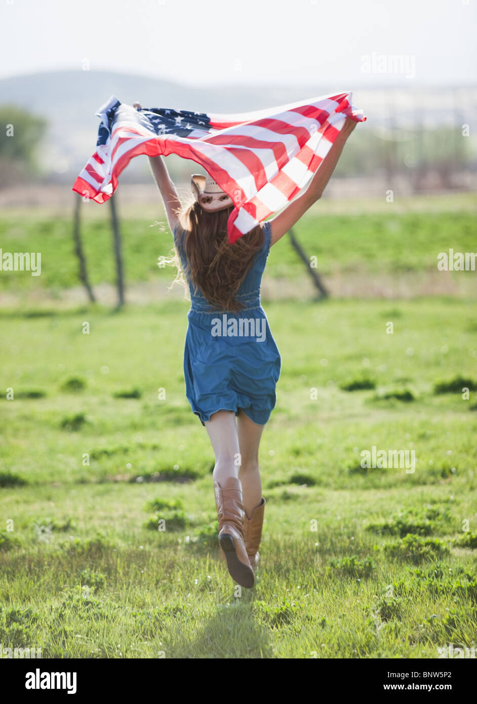 Beautiful cowgirl running with American flag in her arms Stock Photo