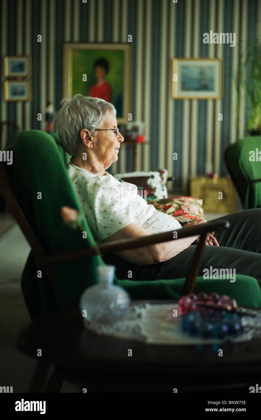 Old woman in profile sitting on living room couch Stock Photo - Alamy