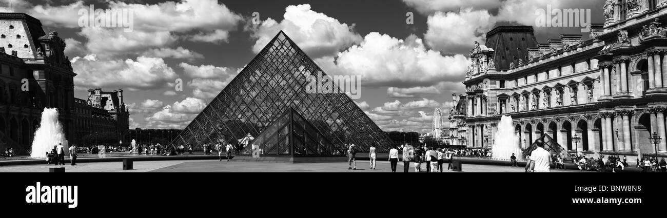 Black and white panoramic view of glass triangle and fountains of famous Louvre art museum Paris, France dramatic sky background Stock Photo