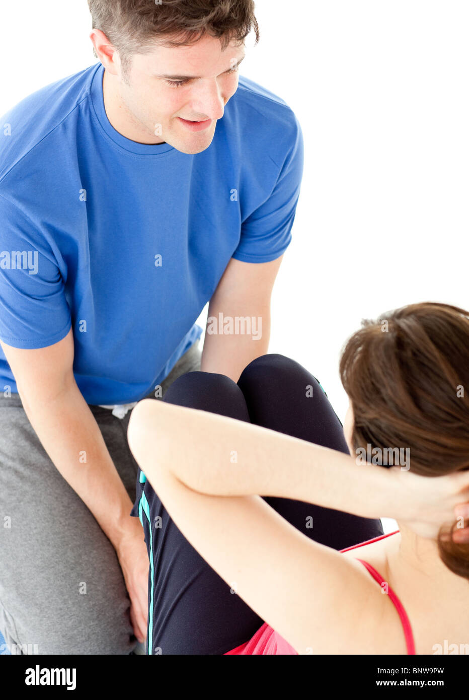 Brunette woman doing sit-ups assited by her personal trainer Stock Photo
