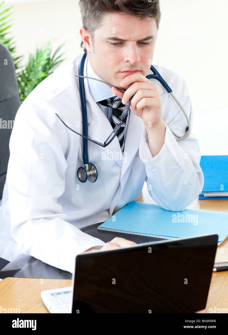 Worried male doctor using a laptop Stock Photo