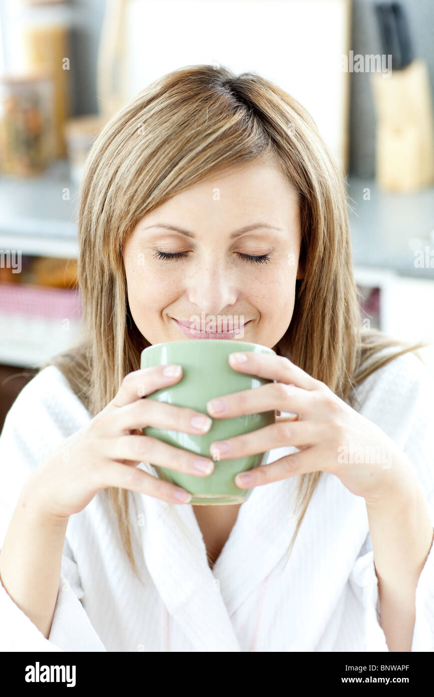 Delighted woman holding a cup a tea  in the kitchen Stock Photo