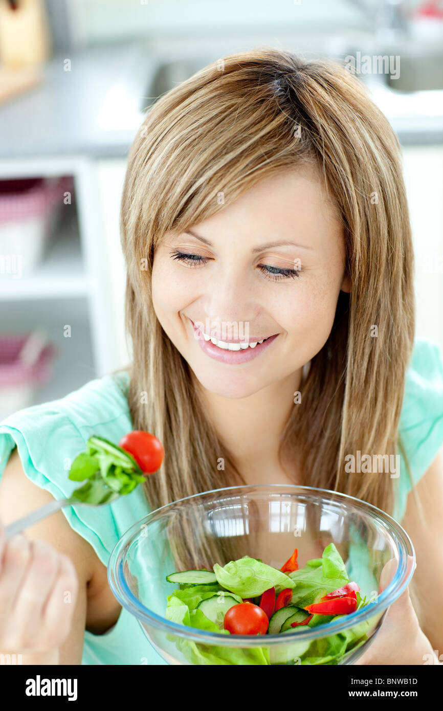 Young woman eating a salad in the kitchen Stock Photo