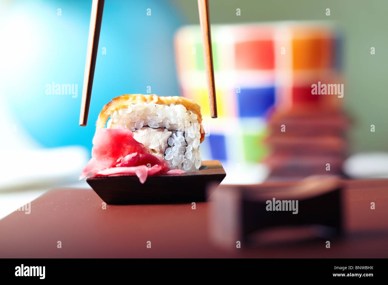 Close-up horizontal photo of the rolled sushi with Philadelphia cheese and tuna on the table and chopsticks Stock Photo