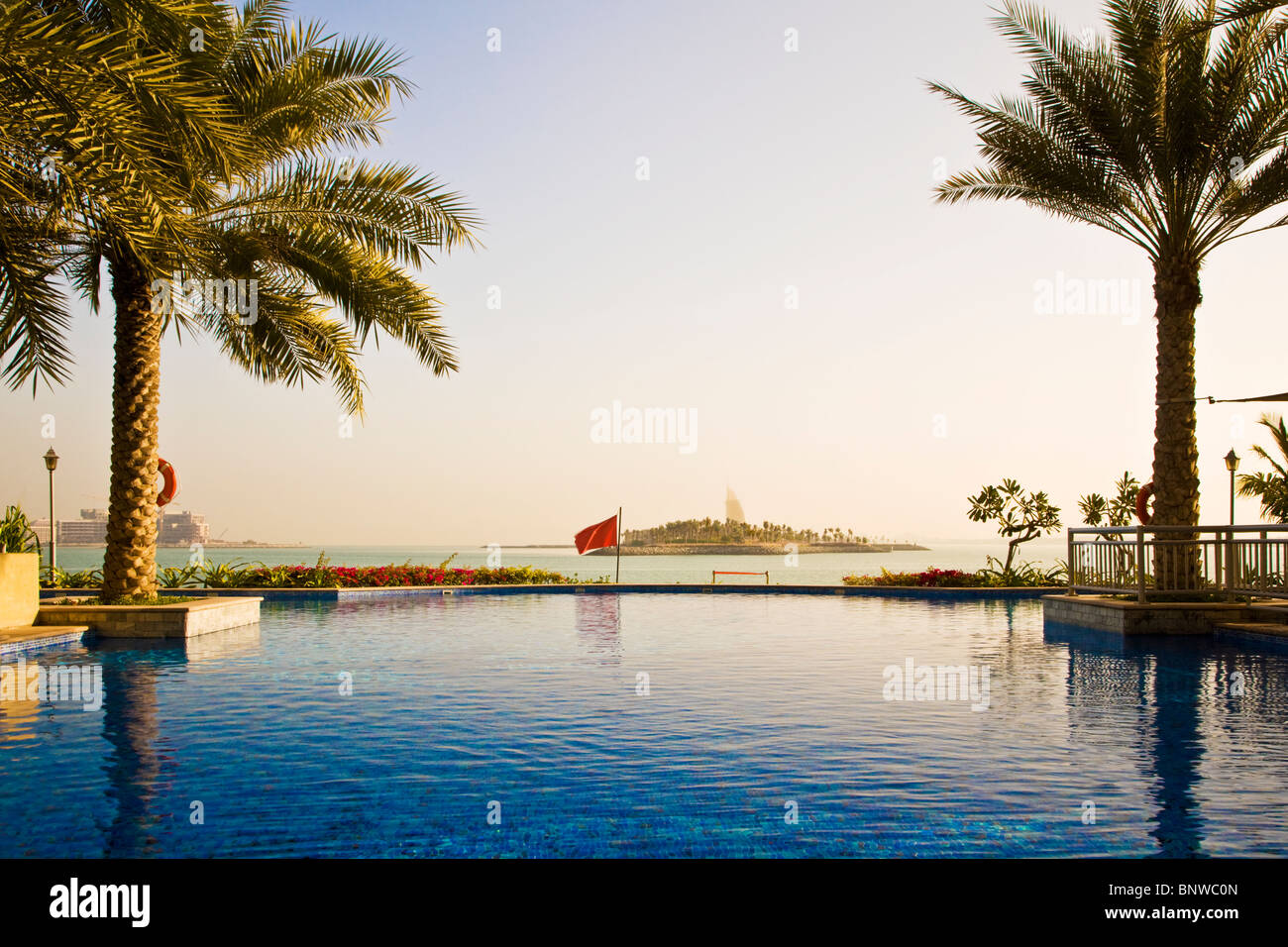 The infinity swimming pool in one of the beach clubs on the Palm Island Jumeira in Dubai. Burj al Arab visible in the distance. Stock Photo