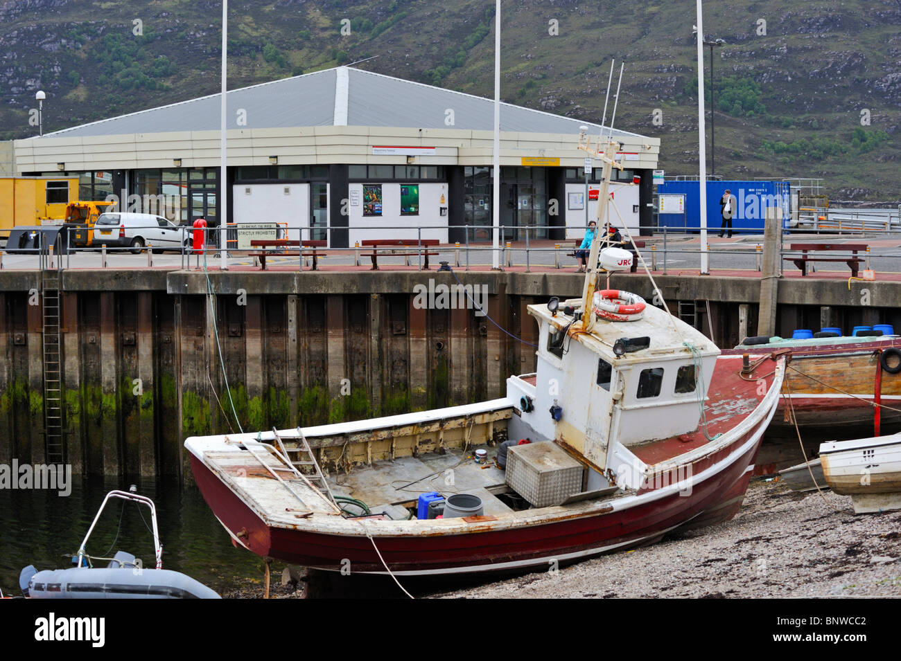 Beached fishing trawler and the Ferry Terminal. Ullapool Harbour. Ullapool, Ross and Cromarty, Scotland, United Kingdom, Europe. Stock Photo