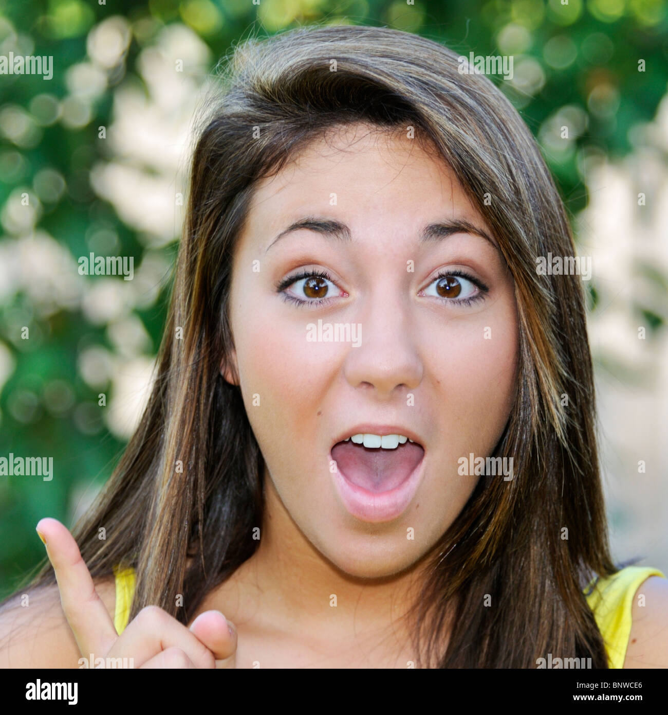A 16 year old pretty Caucasian girl, brown hair, brown eyes,  gestures as if she has an sudden idea. Conceptual image. Stock Photo