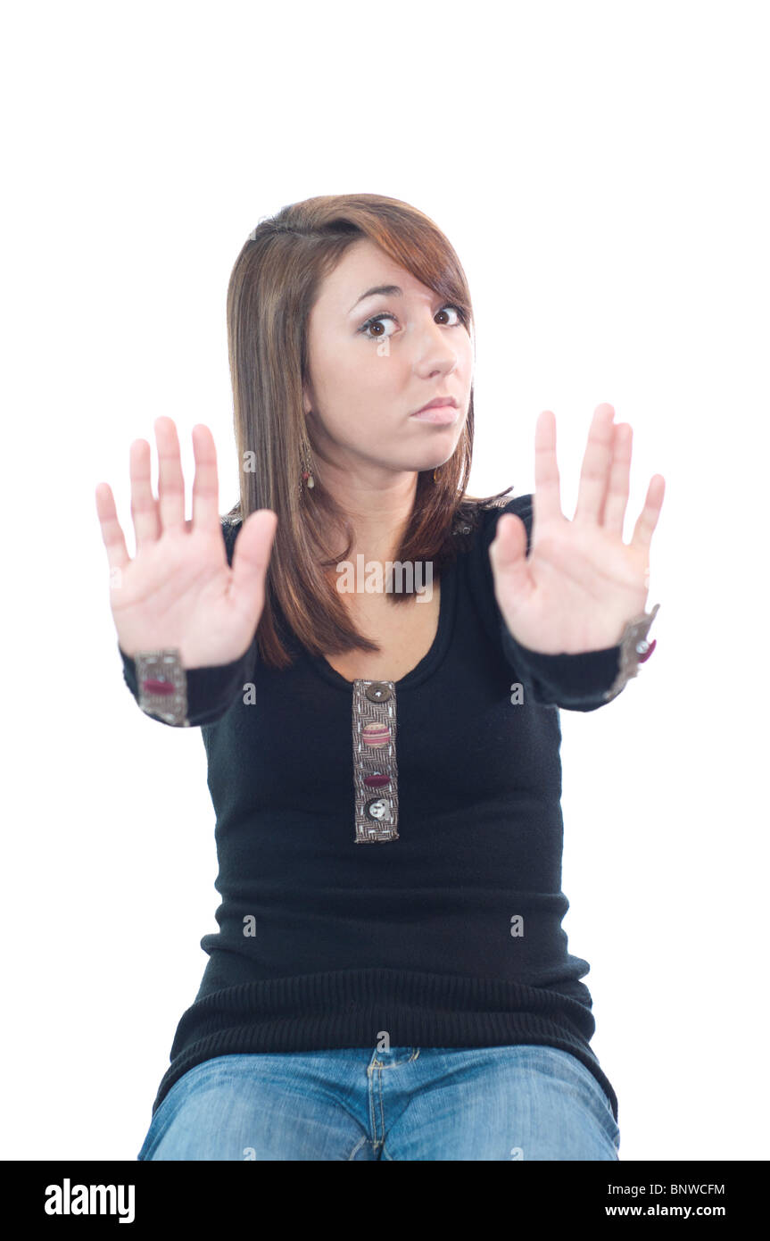 A pretty Caucasian brown-haired, brown-eyed teenage girl pushes her hands out in a warding off gesture. Concepts. USA. Stock Photo