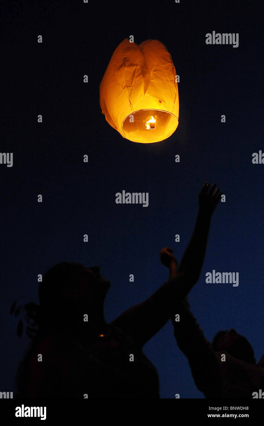 A paper sky lantern is released into the night sky at a wedding