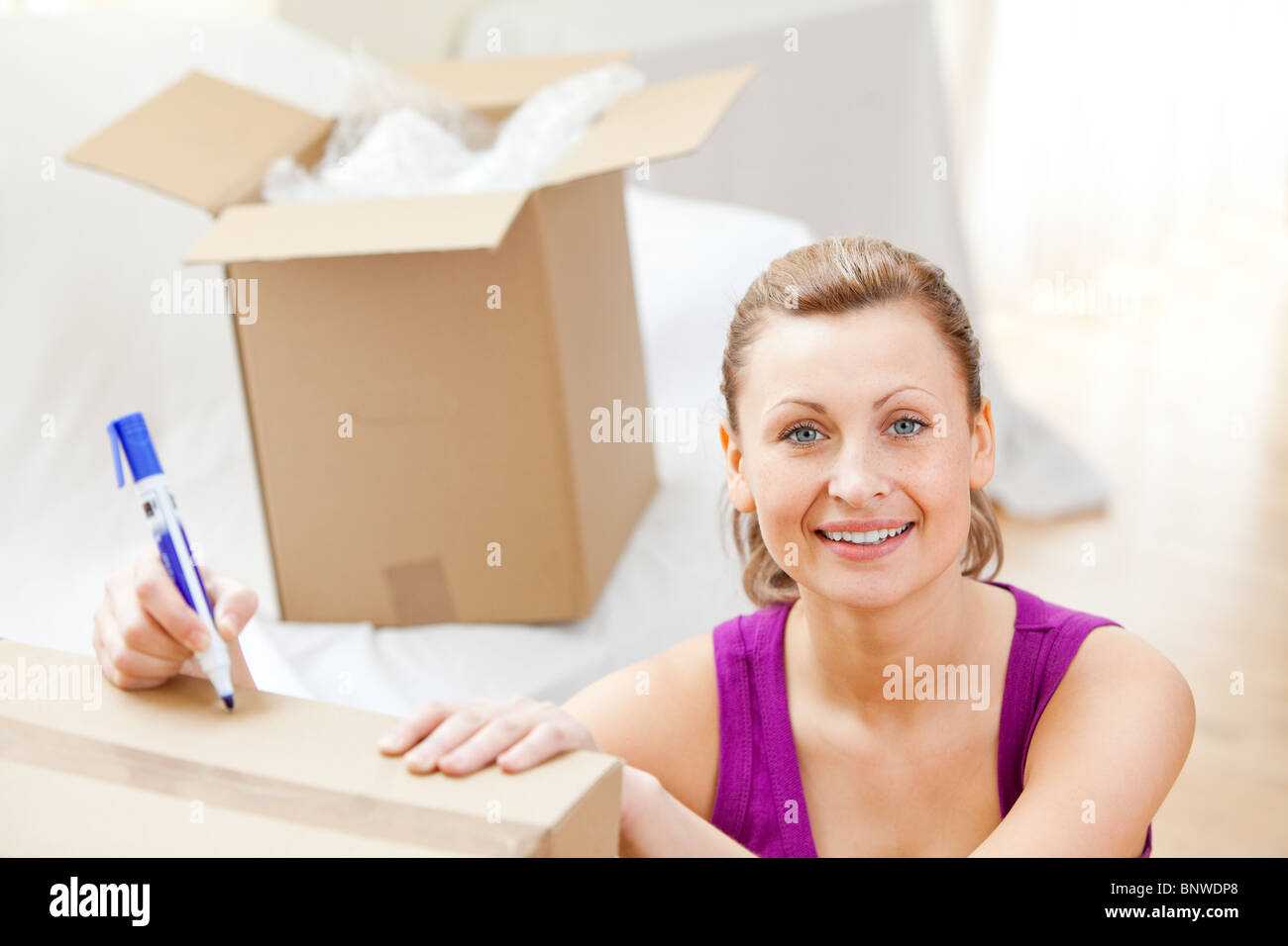 Cute woman writing on boxes using a pen Stock Photo - Alamy