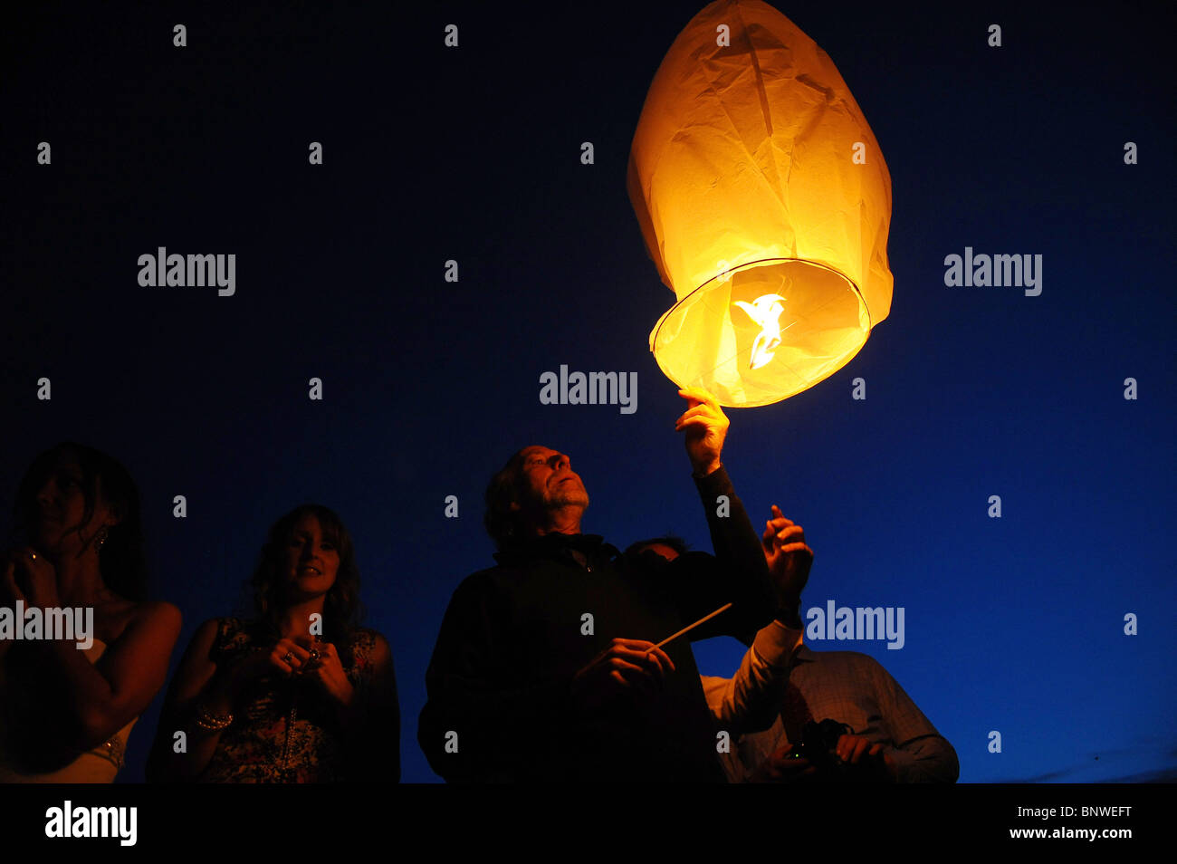 A man releases a paper sky lantern into the dusk sky Stock Photo Alamy