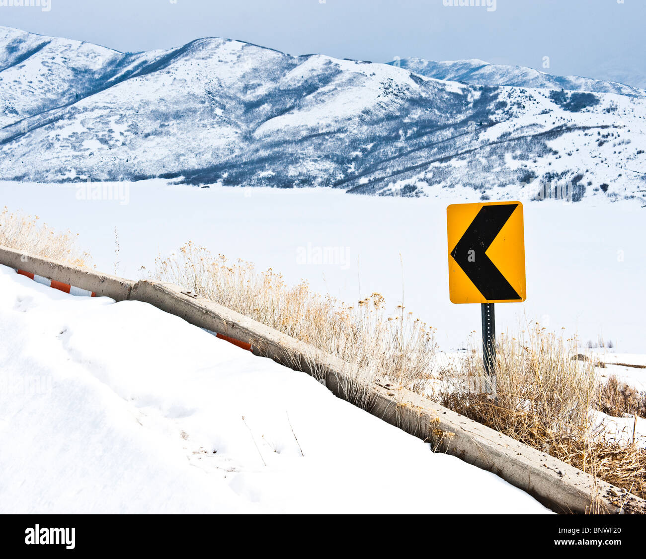 Yellow arrow sharp curve warning sign on mountain road in winter Stock Photo
