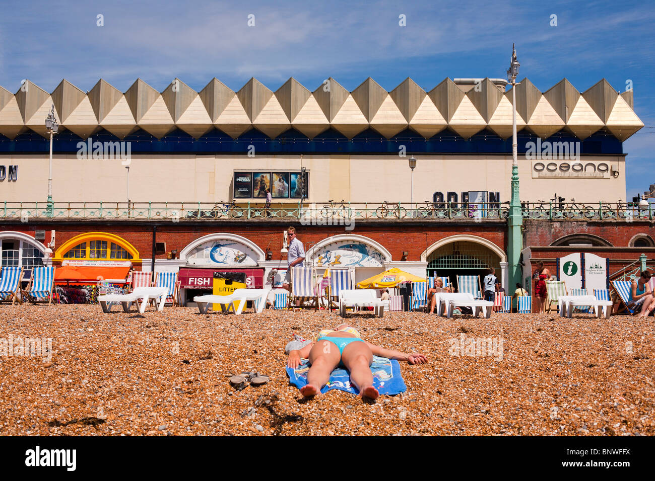 A woman lies in the sun on the beach in Brighton, UK. Stock Photo