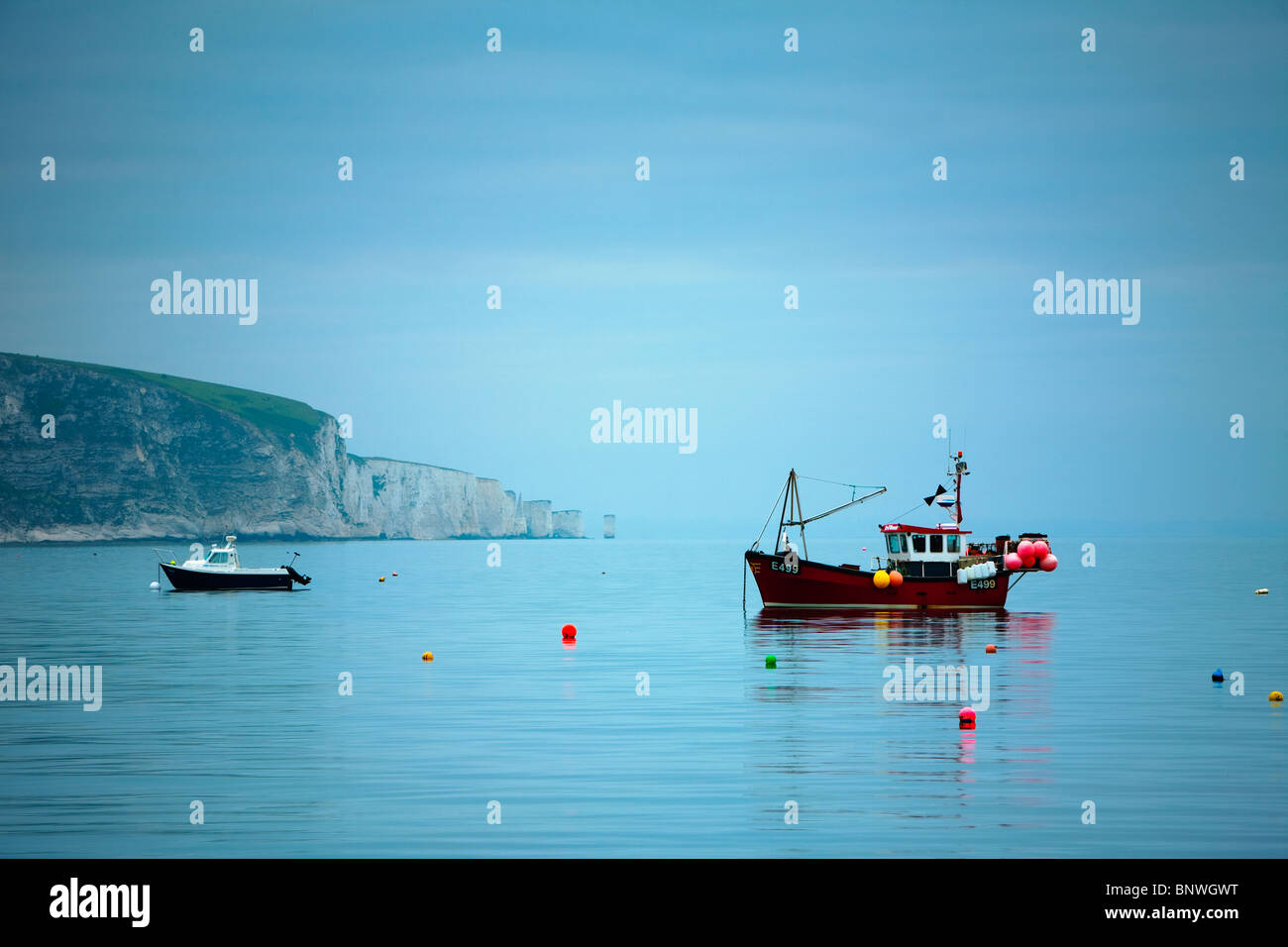 Fishing boats moored in Swanage bay looking towards Old Harry Rocks at dawn, Dorset, Uk Stock Photo