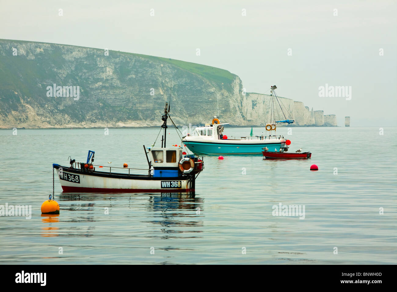Fishing boats moored in Swanage bay looking towards Old Harry Rocks at dawn, Dorset, Uk Stock Photo
