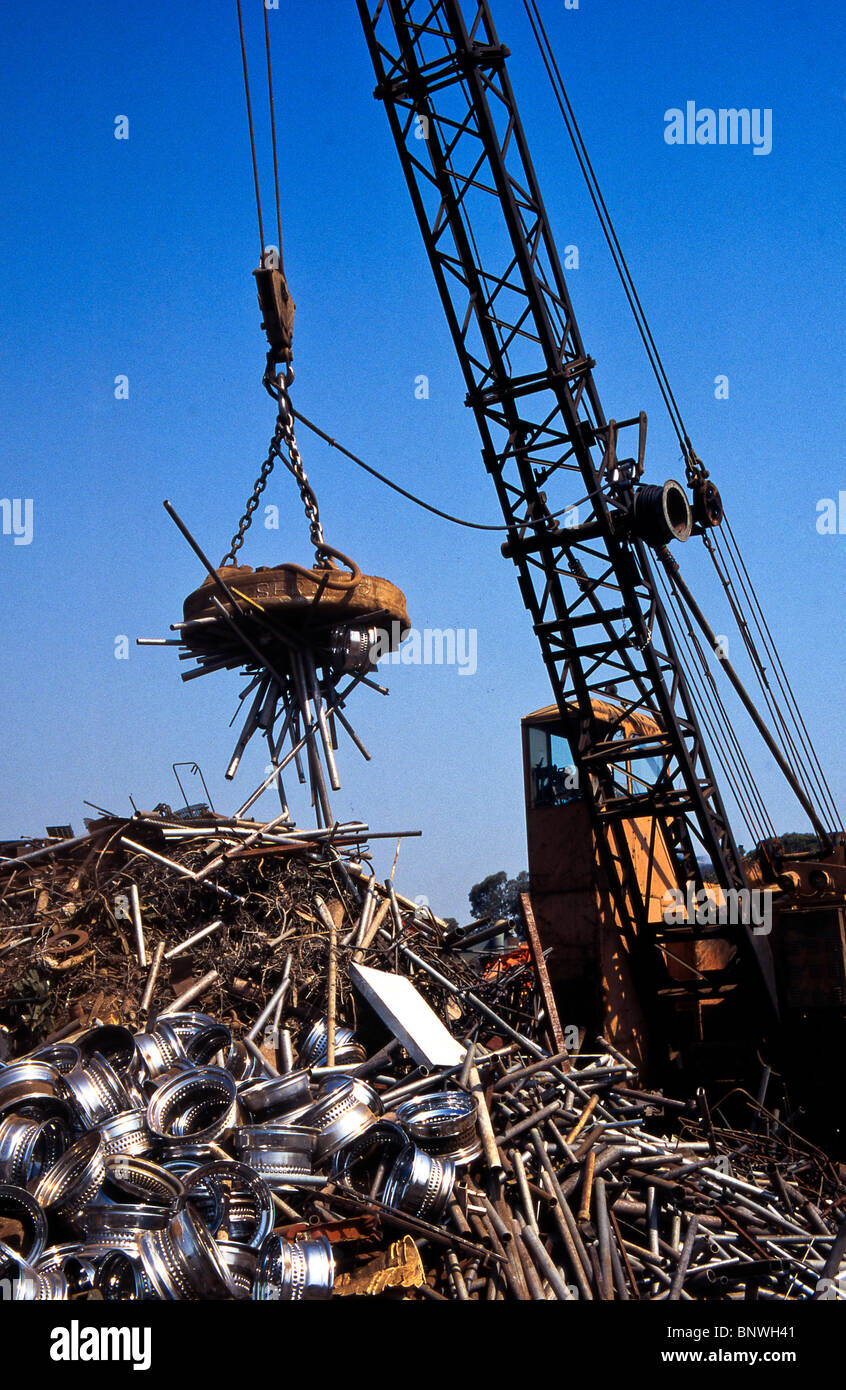 A giant crane-mounted electromagnet is used to move a pile of iron and steel items at a scrap yard in Carson, California. Stock Photo