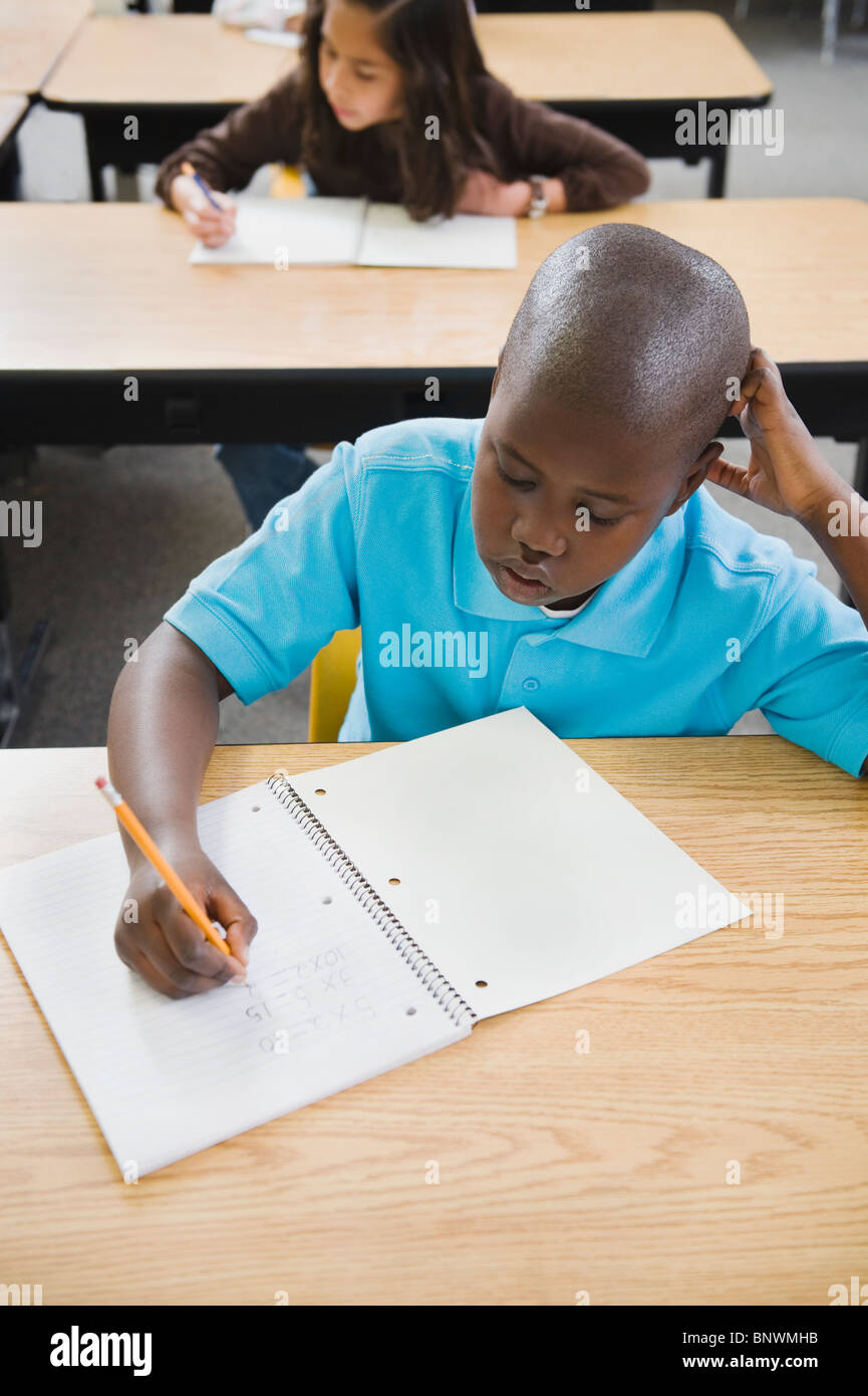 Elementary students writing in notebooks at their desks Stock Photo Alamy